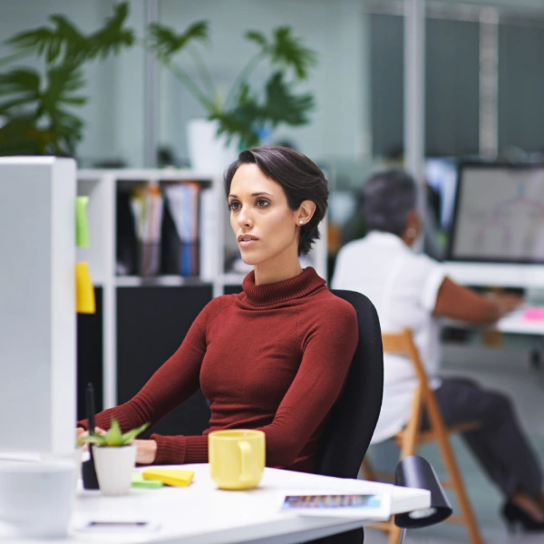 Woman sitting at a desk and staring at a desktop computer screen