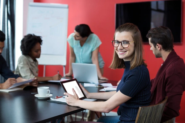 Confident woman smiling while holding a tablet, representing AI-powered innovation and digital confidence.